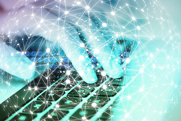 A hand typing on a keyboard with a blockchain graphic